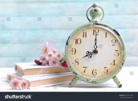 stock-photo-beautiful-flowers-with-clock-and-book-on-table-on-light-blue-background-229972999